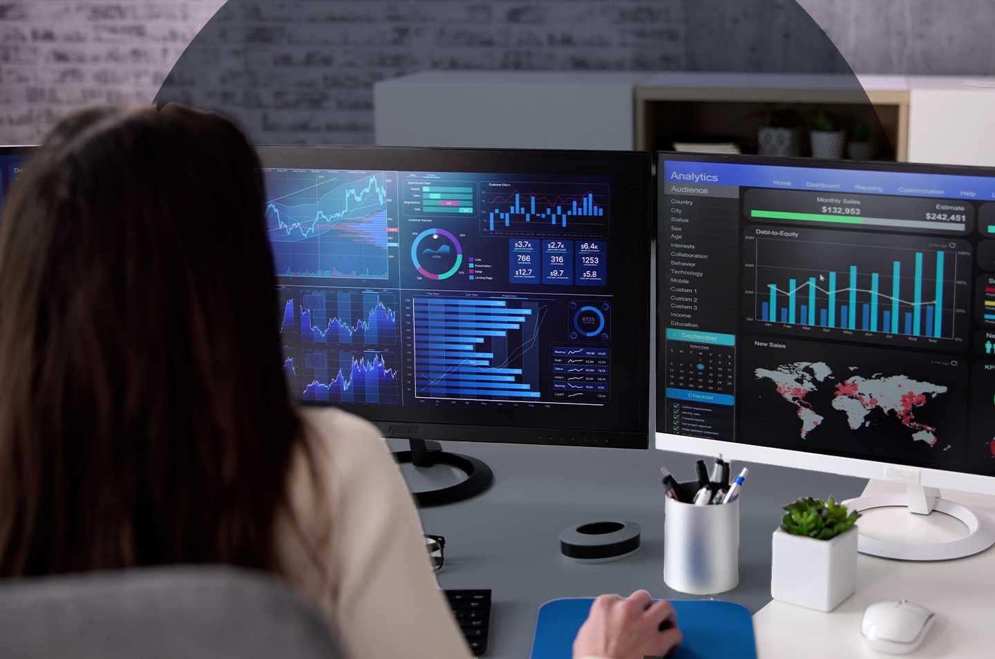 a woman sitting in front of a computer monitor looking at data dashboards