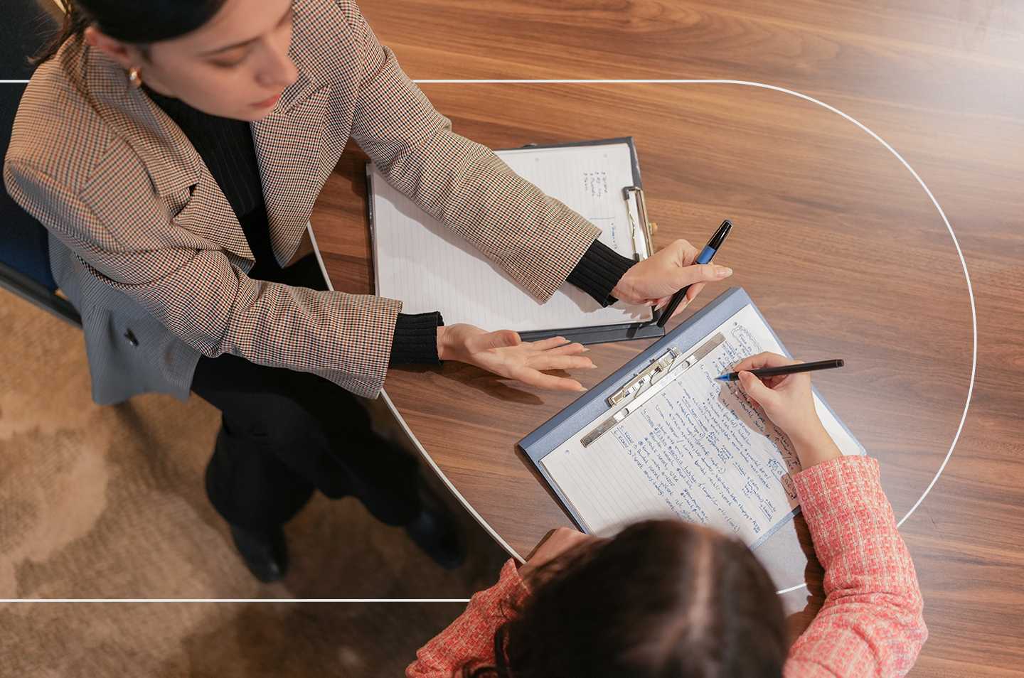 two people sitting at a table writing on notepads