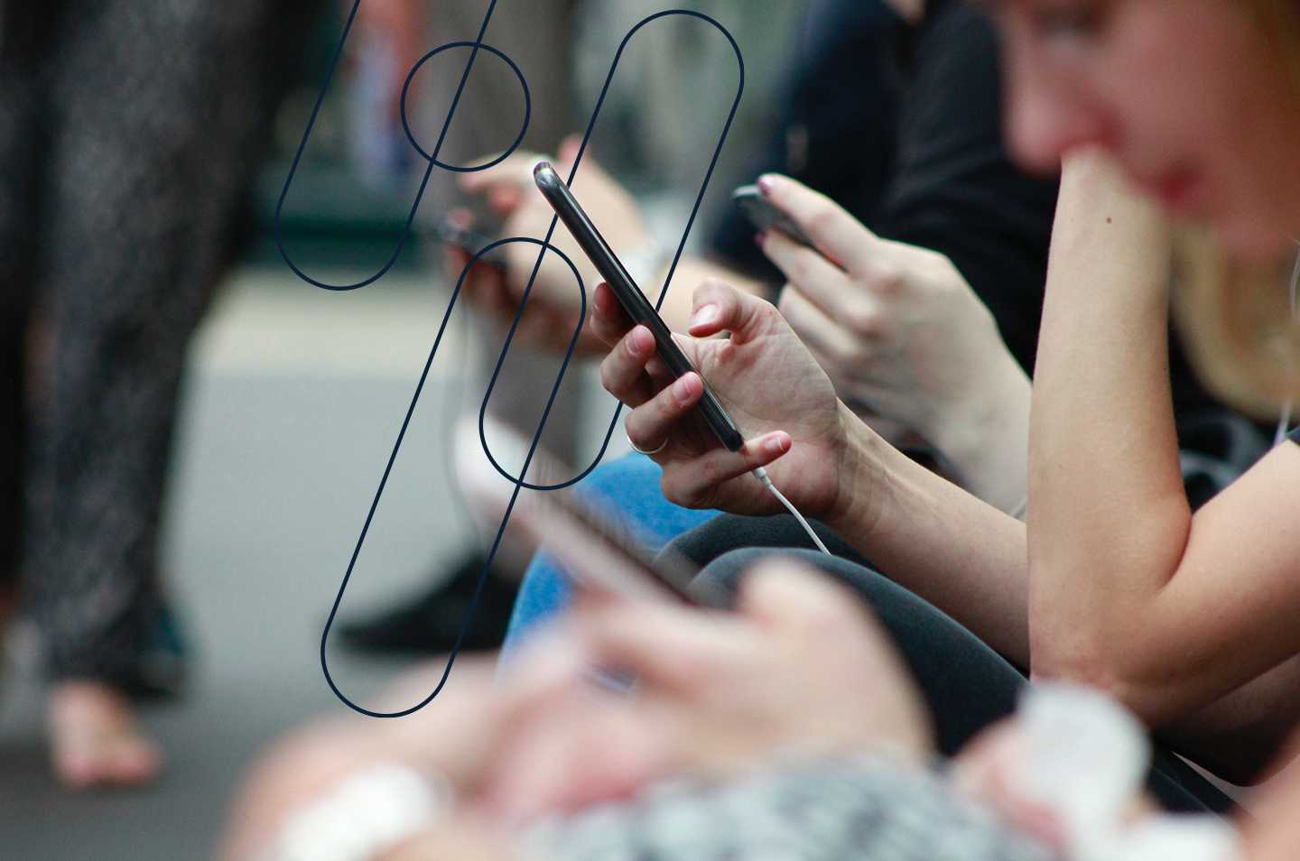 people sitting in a row with a focus on a pair of hands holding a smart phone